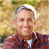 Man in red plaid shirt smiling outdoors