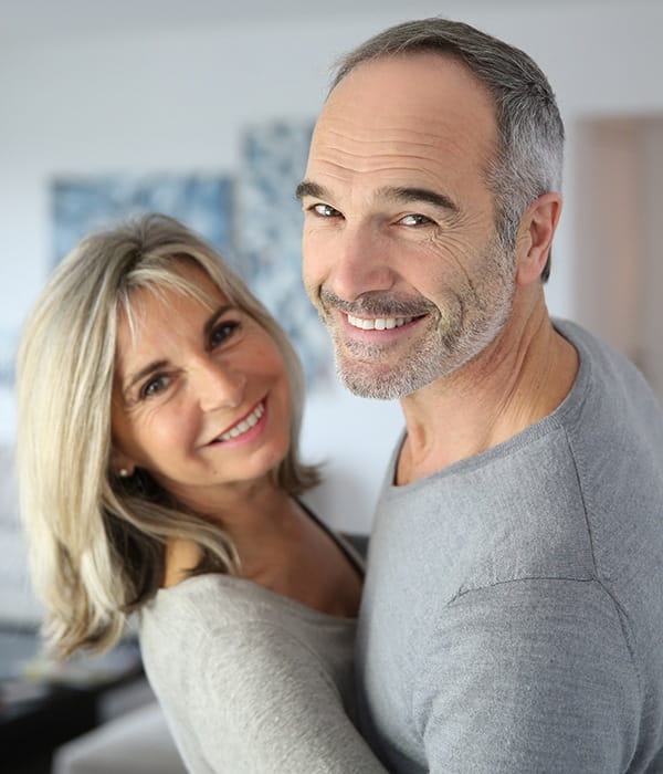 Smiling couple with dental implants in Greensboro 